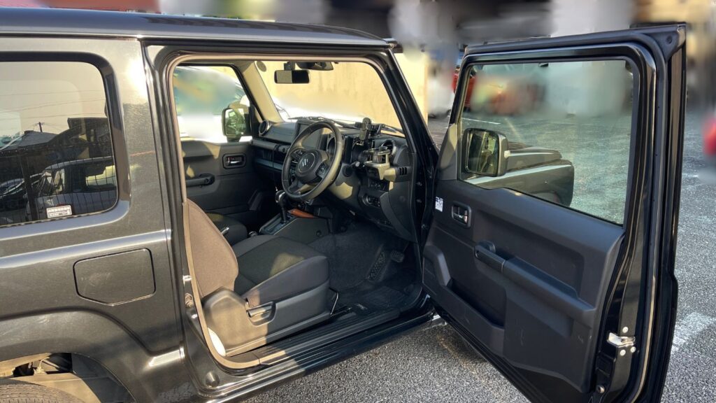 ジムニーJB64の運転席ドアを開けた状態。足元レバーや室内の様子が見える写真。