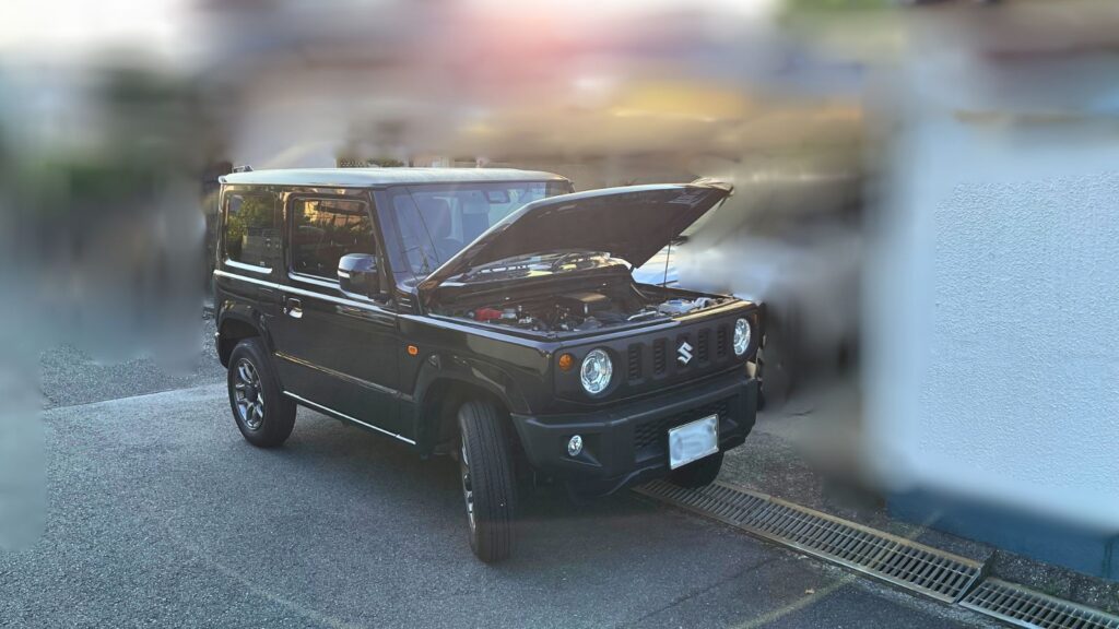 スズキ・ジムニーJB64のボンネットを開けて出発前点検を行っている様子の写真