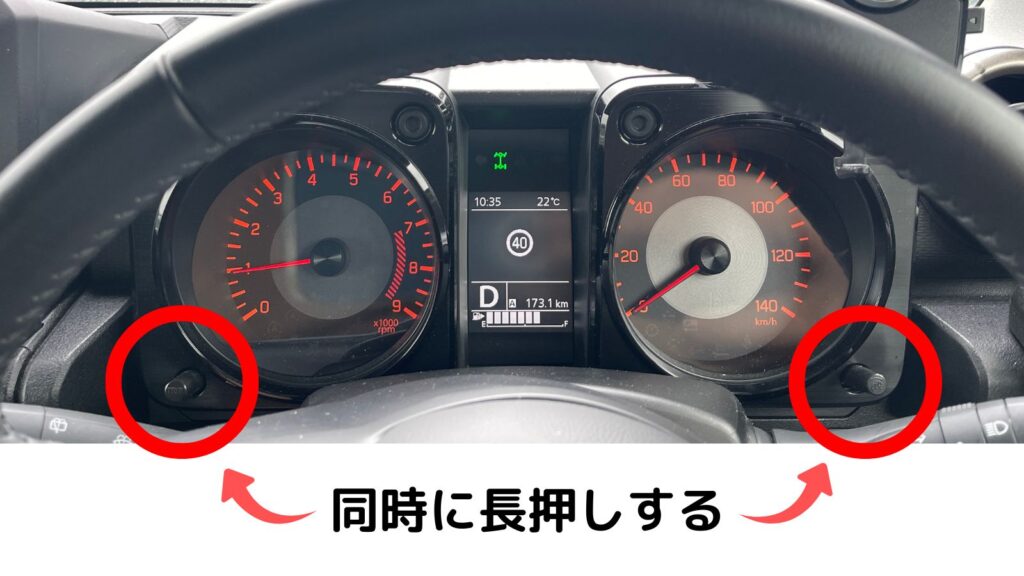 ジムニーJB64のメーターパネル。時計の時刻を合わせるため、左右にあるトリップノブと表示切替ノブを同時に長押ししている様子。