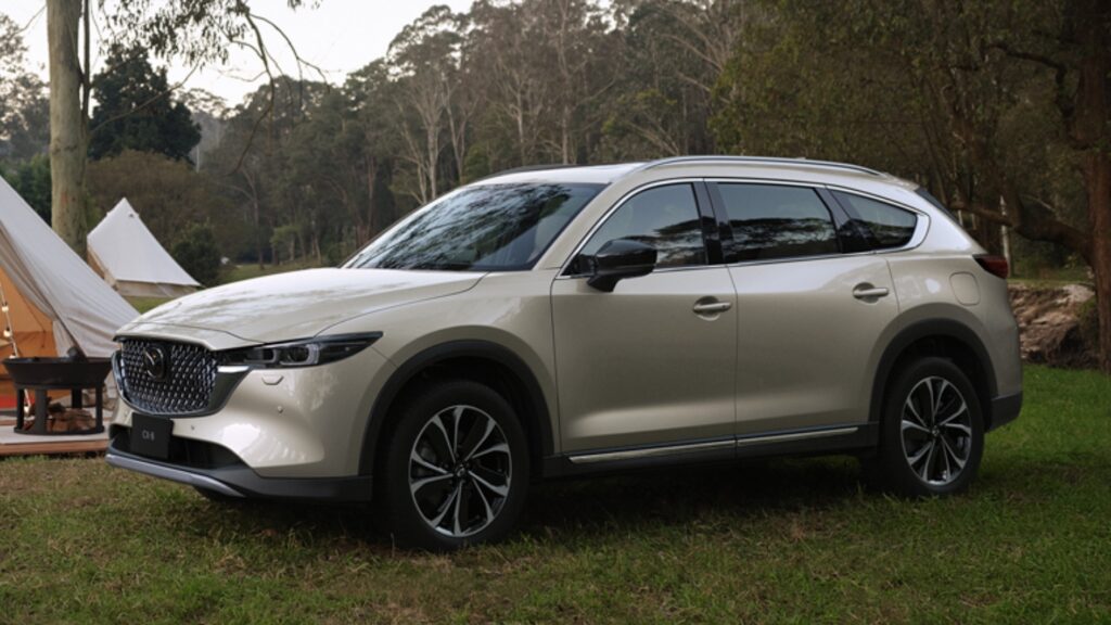 後部座席が広く豪華な3列シートSUV、マツダCX-8。キャンプサイトでくつろぐ様子。