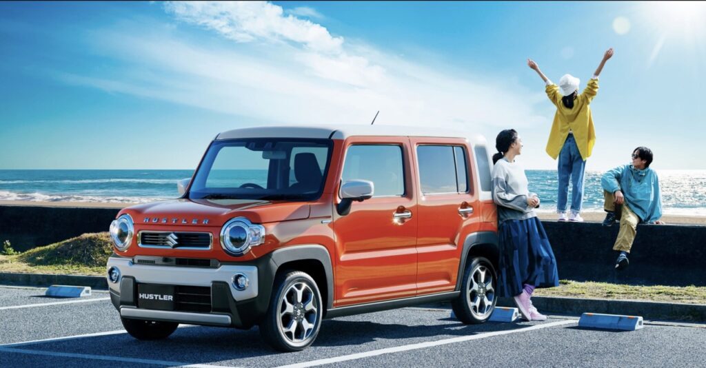 海辺に停まるオレンジ色のスズキ ハスラー。この記事では、ジムニー乗りが「ハスラーは運転しにくいのか」を2週間の実体験に基づき正直にレビューします。