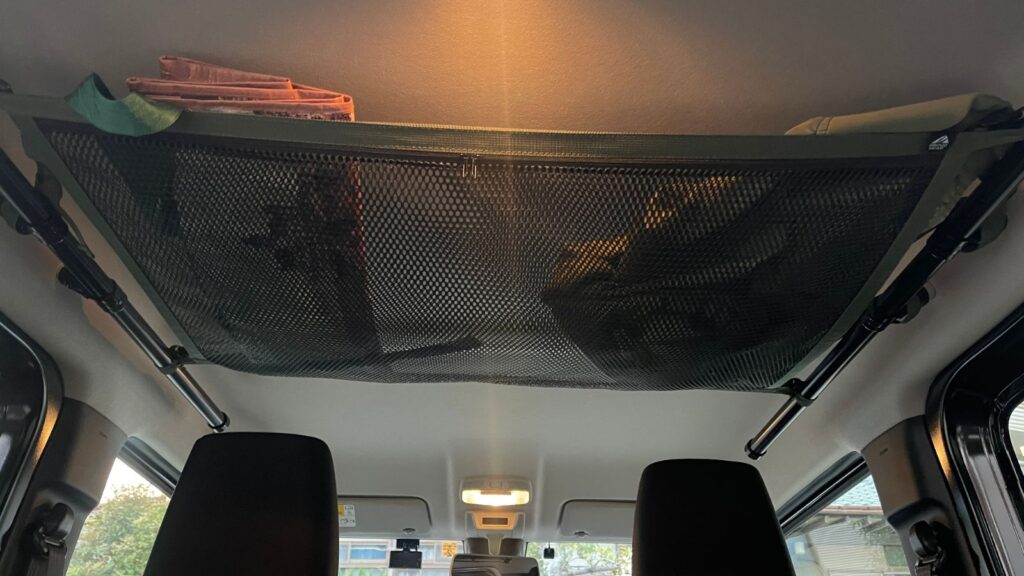 ジムニーJB64の車内天井に取り付けた収納ネットへ、コストコのエコバッグやジャケットなどの軽い小物を薄く載せている実録写真