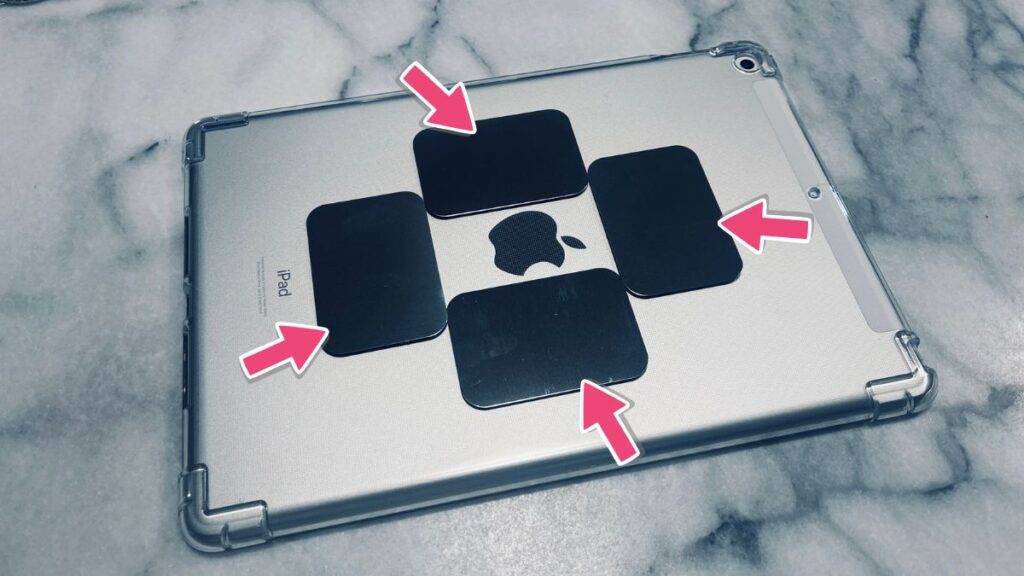iPad第9世代に装着したクリアケースの背面に、Appleロゴを囲むように貼り付けられた4枚の黒い鉄板プレートと、それぞれのプレートを指し示す4本のピンク色矢印